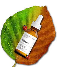 The Ordinary Vitamin C 8% and Alpha Arbutin 2% brightening serum bottle on a colorful leaf for dark spot care